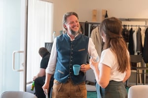 Ein Mann und eine Frau unterhalten sich und trinken ein Getränk aus Tassen.